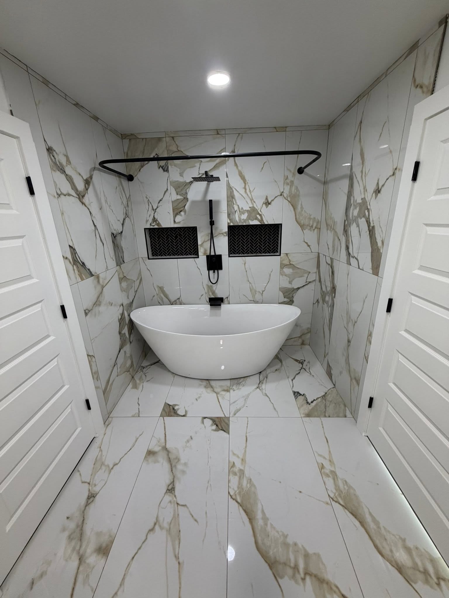 Freestanding bathtub in luxury white stone bathroom by Grandson's Remodeling