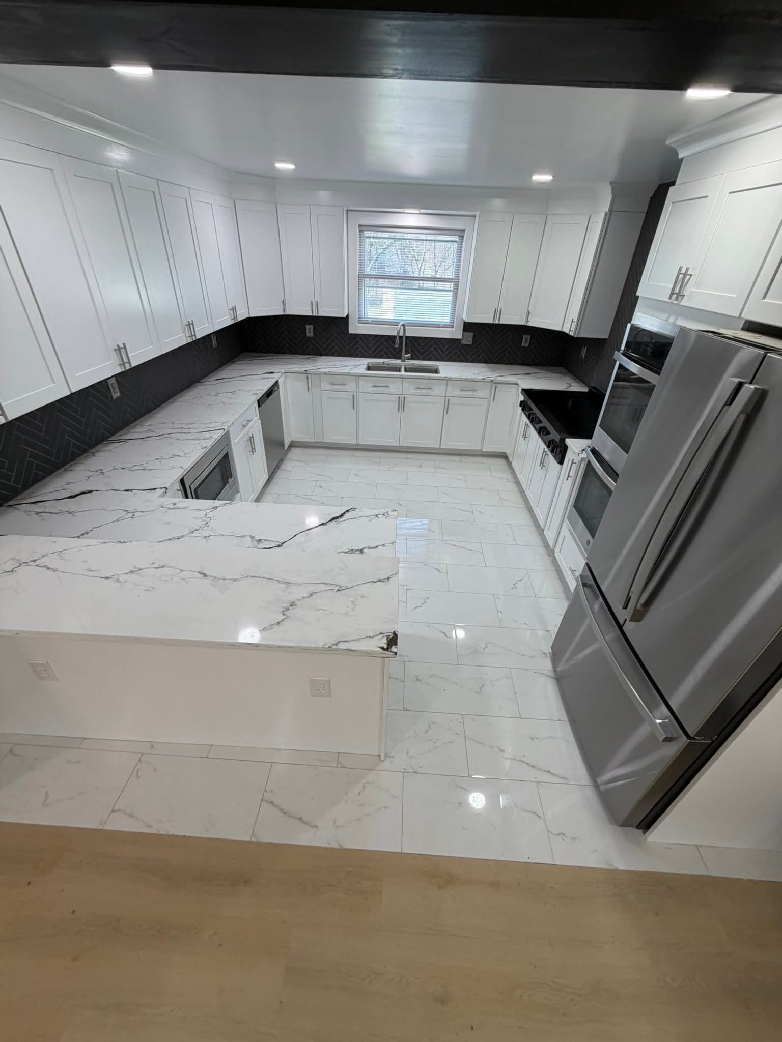 Luxury kitchen remodel with marble countertops and herringbone backsplash by Grandson's Remodeling